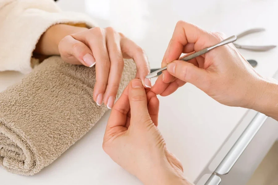 From above nail technician cutting cuticle