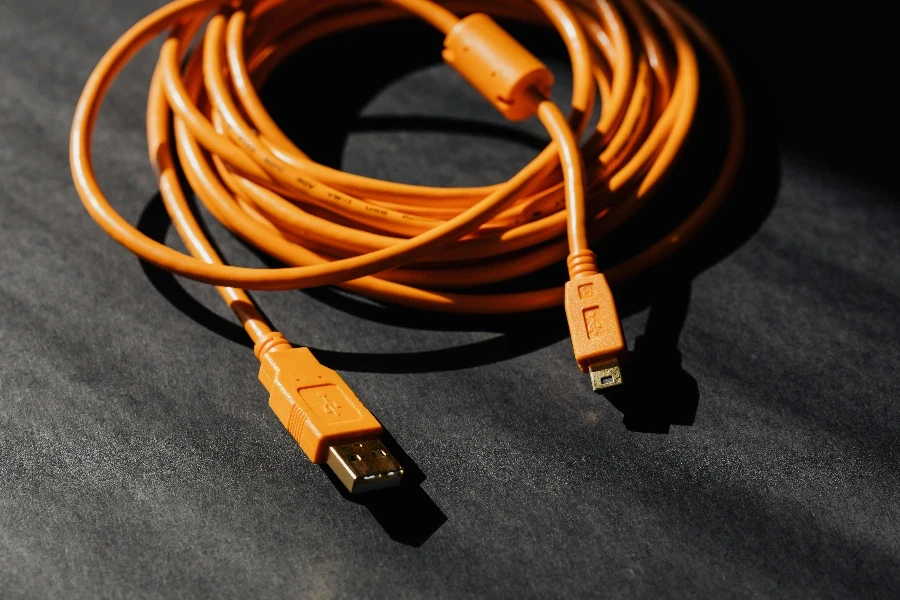 From above of orange usb to micro usb cable twisted into ring placed on black board