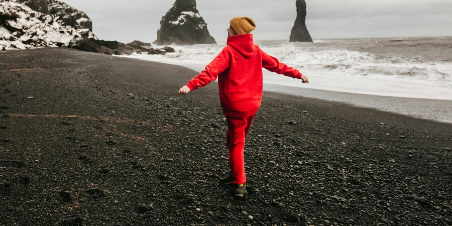 Girl in Red Sweatsuit Walking on Seashore