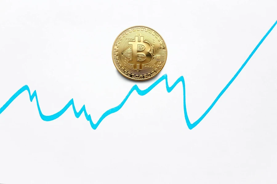 Gold bitcoin cryptocurrency coin and blue graph of changes of value on white background 