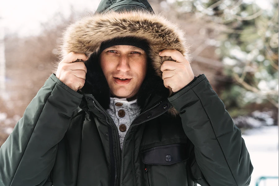 Handsome smiling bearded man in hooded jacket on winter day