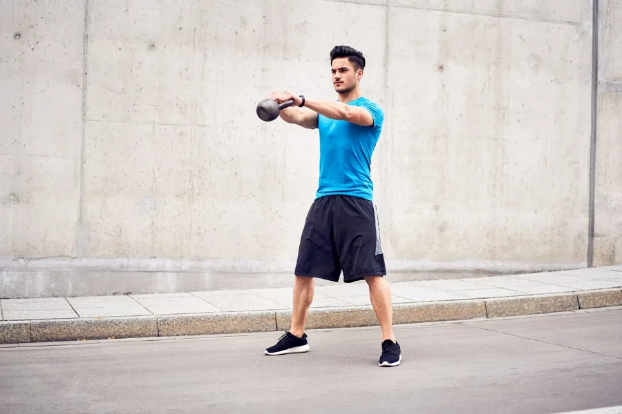 Health and fitness concept. Man doing kettlebell swing exercises during urban workout session