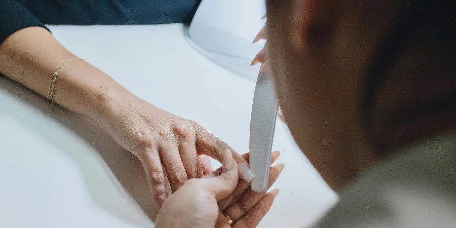 A Manicurist Filing a Clients Nail