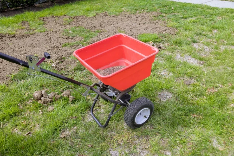 In back yard of residential property, lawn grass seeds are sown using drop lawn spreader