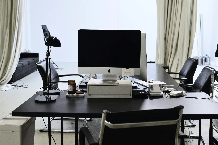 Interior of convenient workspace with contemporary computer placed on table with lamp in modern light office with couch against window