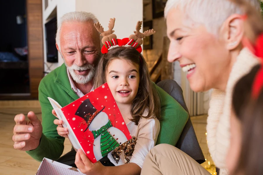 Joyful older couple reading Christmas card to their granddaughters