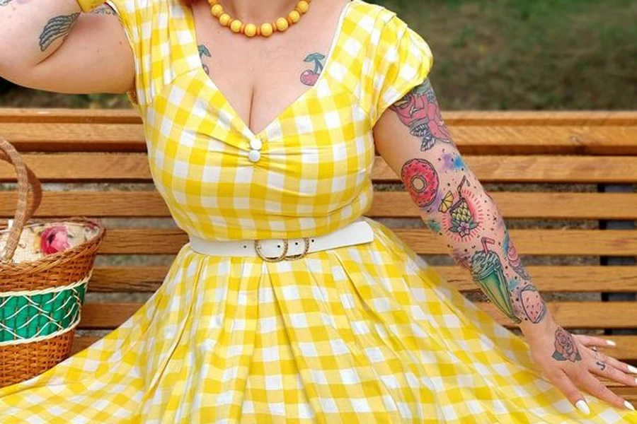 Lady sitting on a bench in a yellow, vintage-inspired gingham dress
