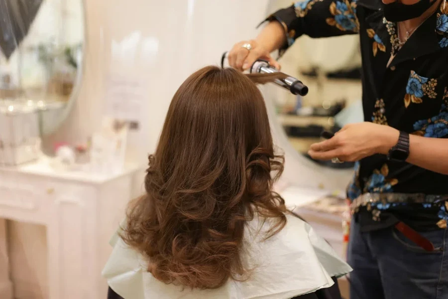 Male hairdresser ironing a woman's hair