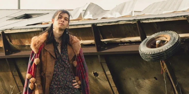 Мужчина позирует в винтажной одежде у перевернутого трейлера