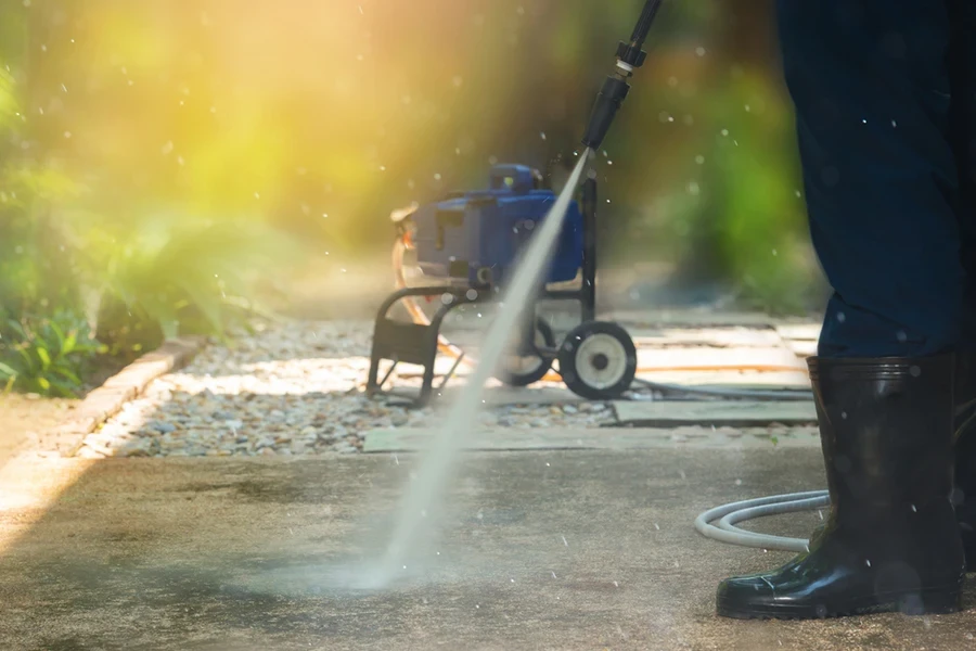 Man cleaning dirty walkway with high pressure water cleaner