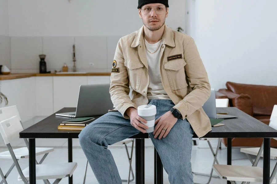 Man in Brown Coat Sitting on Desk