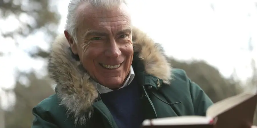 Man in Green Winter Jacket Holding a Brown Book by Andrea Piacquadio