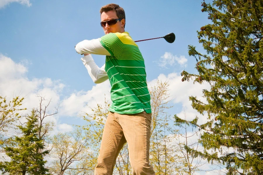 Man in Green and White Stripes Long Sleeve Shirt Holding Black Golf Club