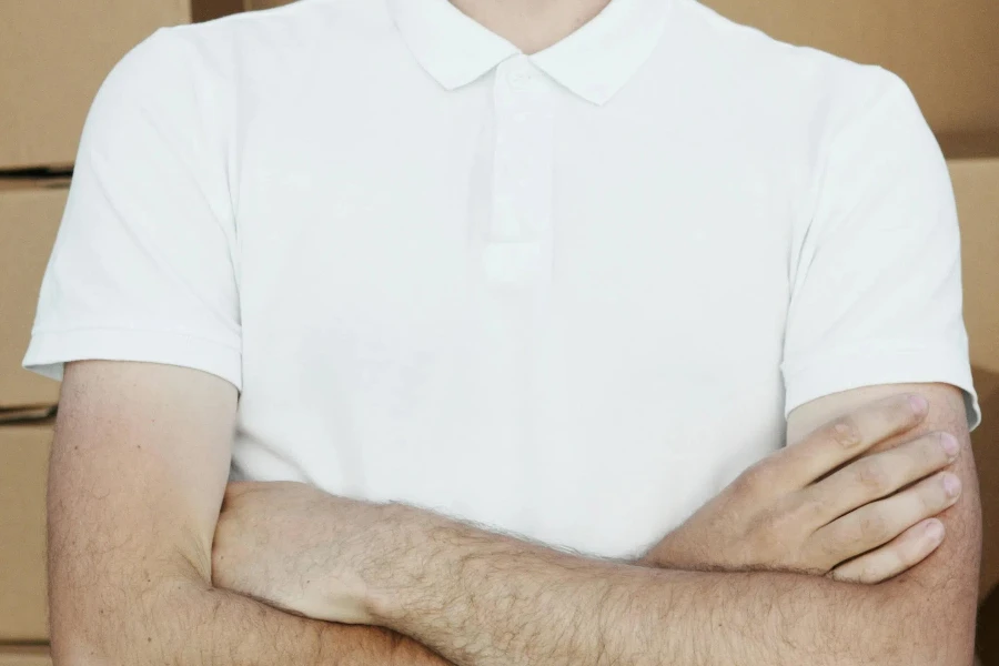 Man in White Polo Shirt and Black Facemask with Arms Crossed