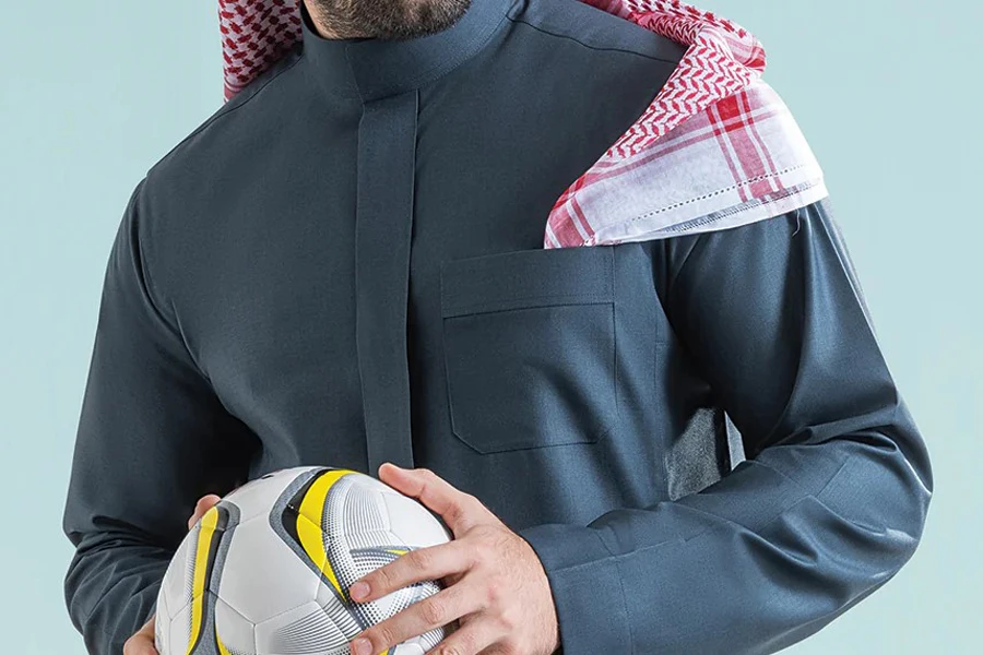 Man in a black Saudi Arabian thobe holding a ball