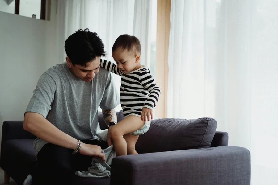 Man in gray T-shirt helping boy in stripe sweater wearing pants