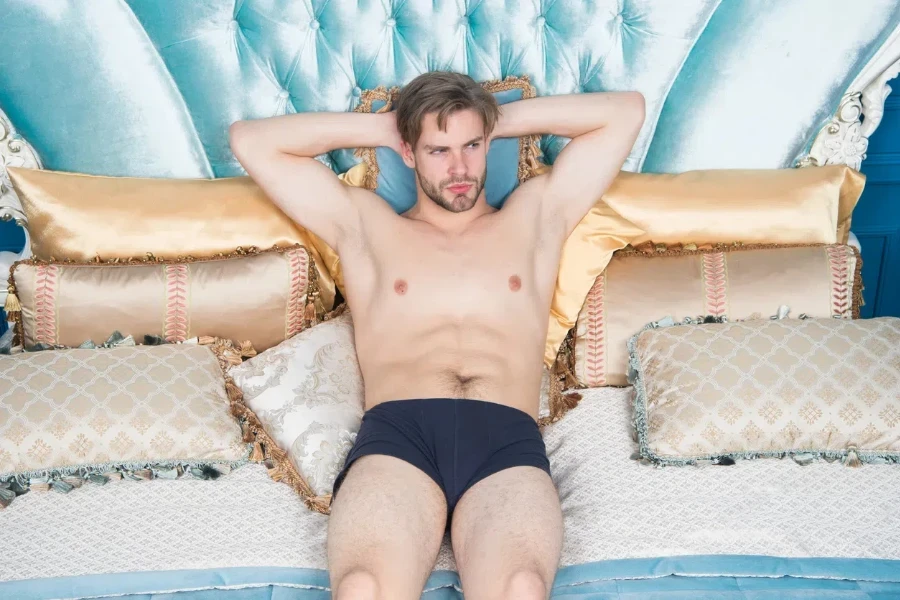 Man in underpants relaxing on bed luxury bedroom