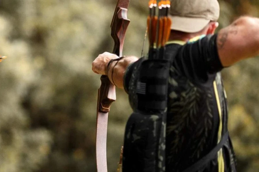 Man shooting an arrow while wearing a back quiver