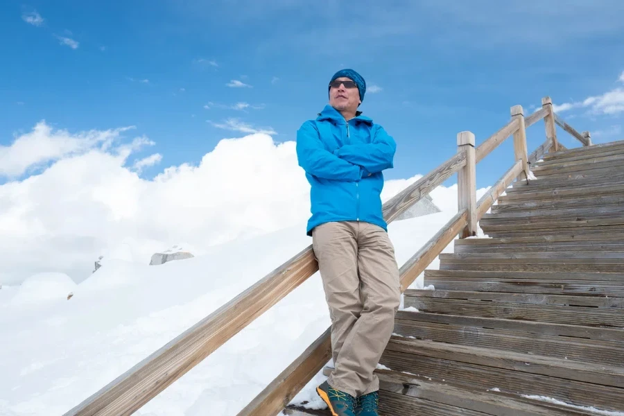 Man standing on wooden boardwalk on snowy mountain, 4860-meter Dagu Glacier, Sichuan, China