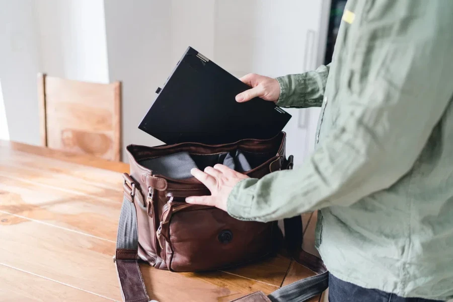 Uomo che tira fuori un laptop da una borsa