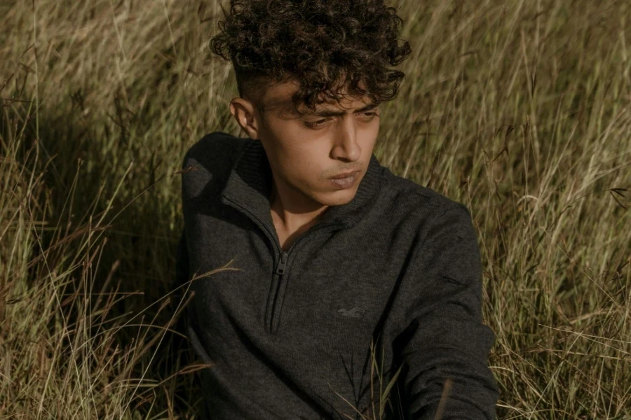 Model in a Gray Zipper Sweater Sitting in the Tall Grass