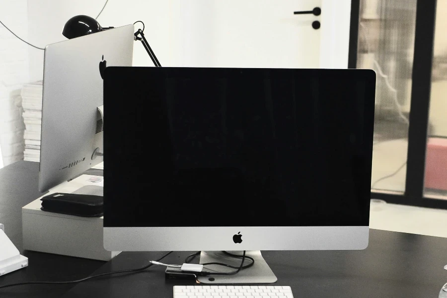 Monitor with black screen of modern computer placed on black table with white keyboard and mouse in workspace