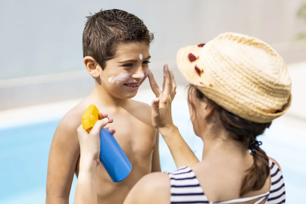 Mother aplying sunscreen to her son on a summer day