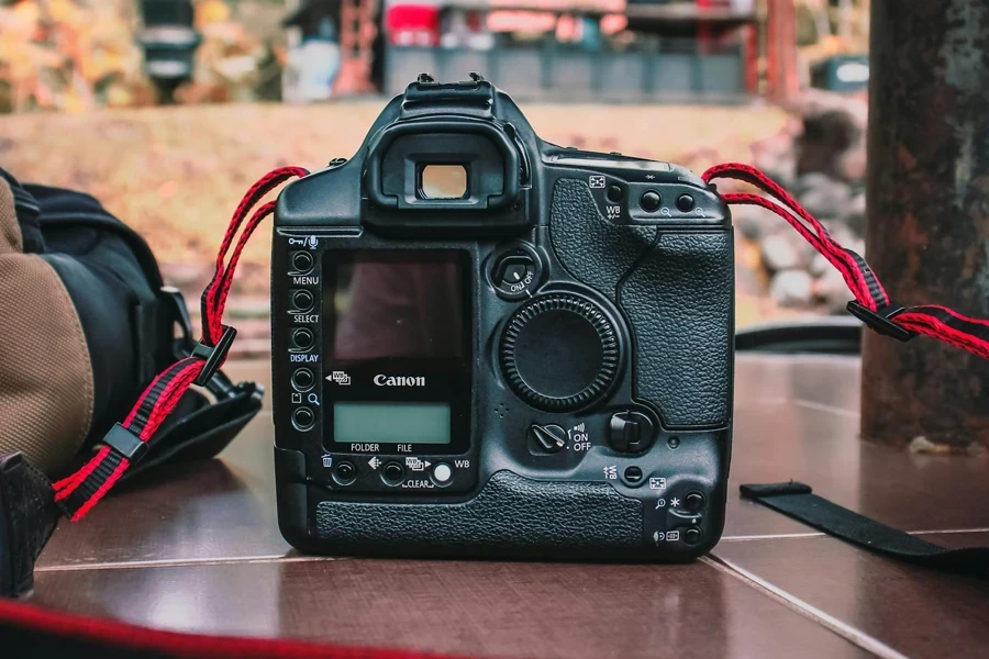 Outdated camera with viewfinder and lsd screen near user controls placed on ground with red stripe in street during day