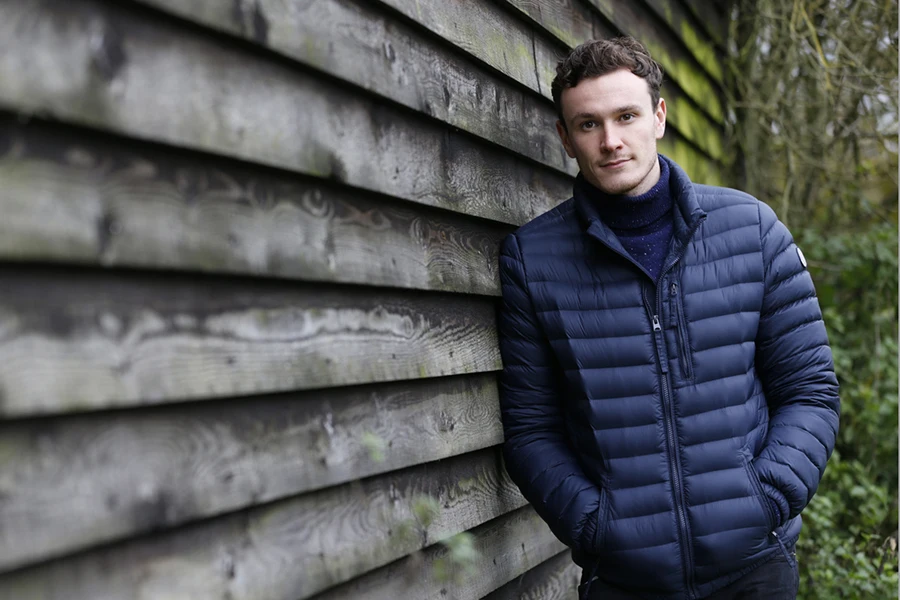 Outdoor Portrait Of Man Leaning Against Wooden Building