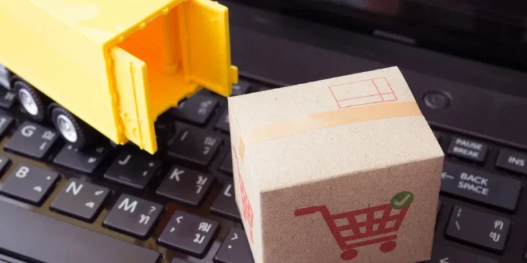 Parcel carton box with shopping trolley cart printing and delivery truck on laptop computer background