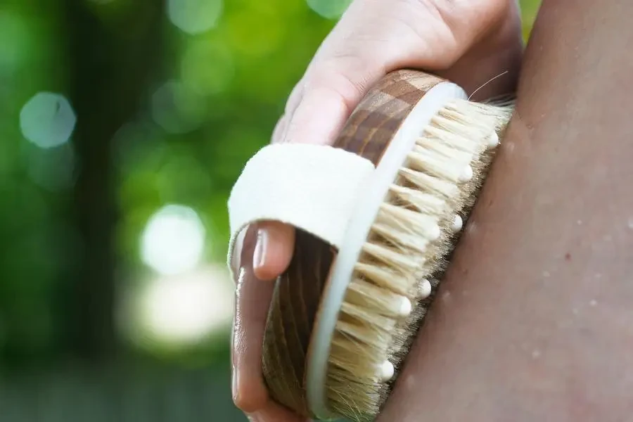 Person Holds A Wooden Exfoliator Against Their Leg