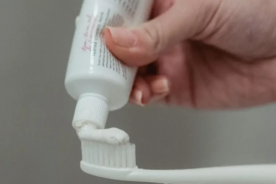 Person Putting Toothpaste On Toothbrush by Miriam Alonso