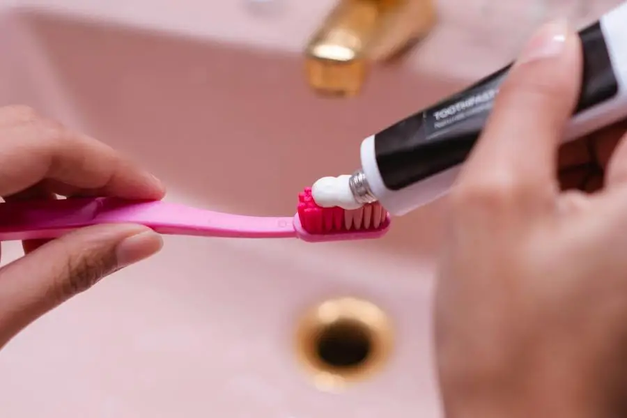 Person Putting Toothpaste On Toothbrush by Ron Lach