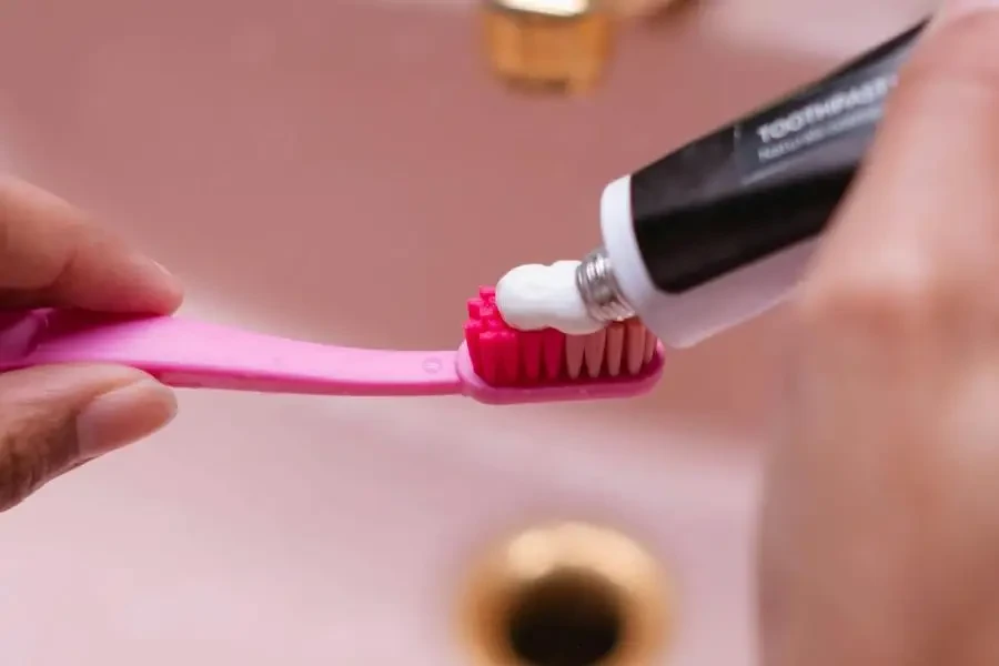 Person Putting Toothpaste On Toothbrush by Ron Lach