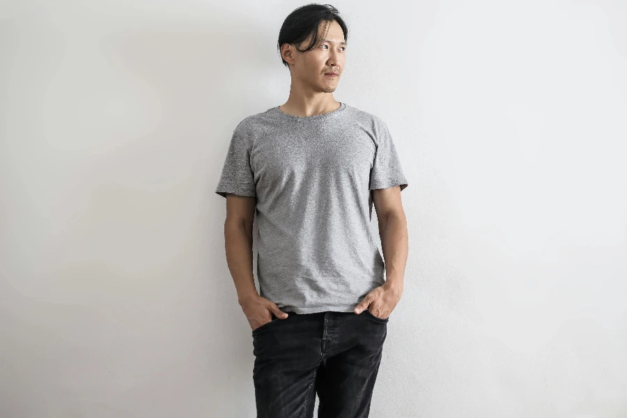 Man in Gray T-shirt and Black Denim Jeans Standing In Front of Gray Wall