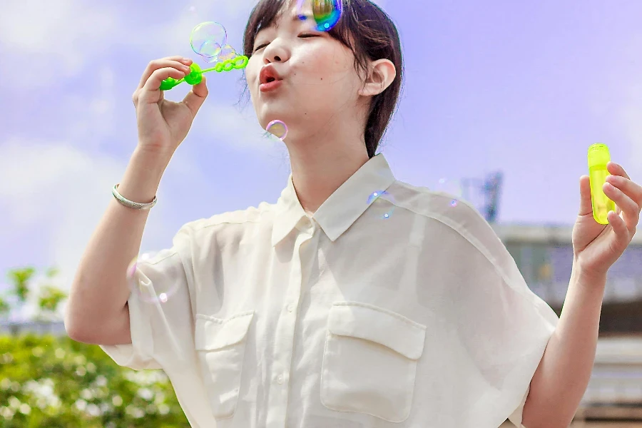 Photo of Woman in White Blouse Playing With Bubbles