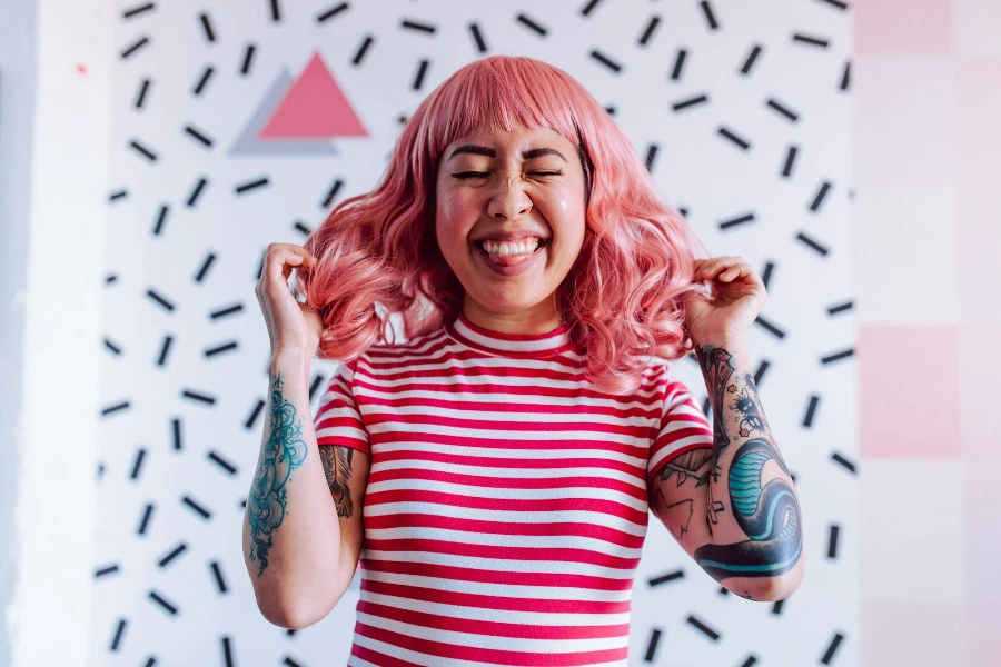 Photo of a Woman with Tattoos Touching Her Pink Hair