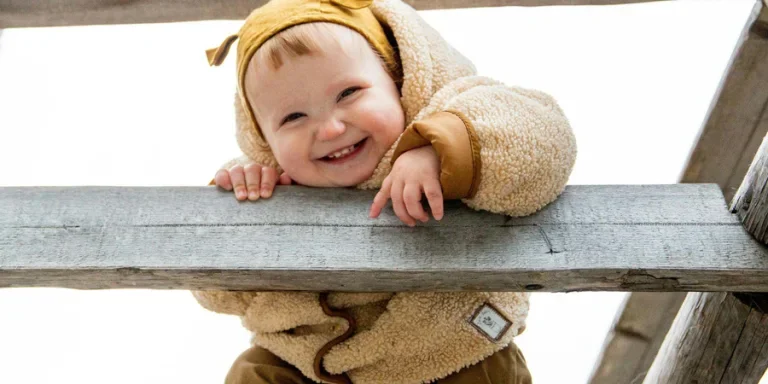 Photo of baby leaning on wooden fence