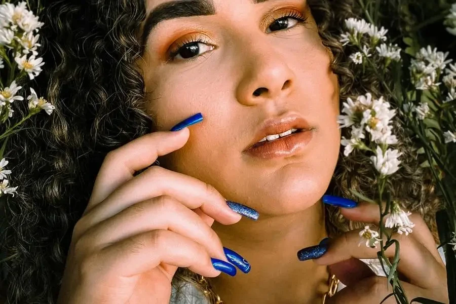 Photoshoot of Woman with White Flowers and Blue Nail Polish by Beatriz Fernandes