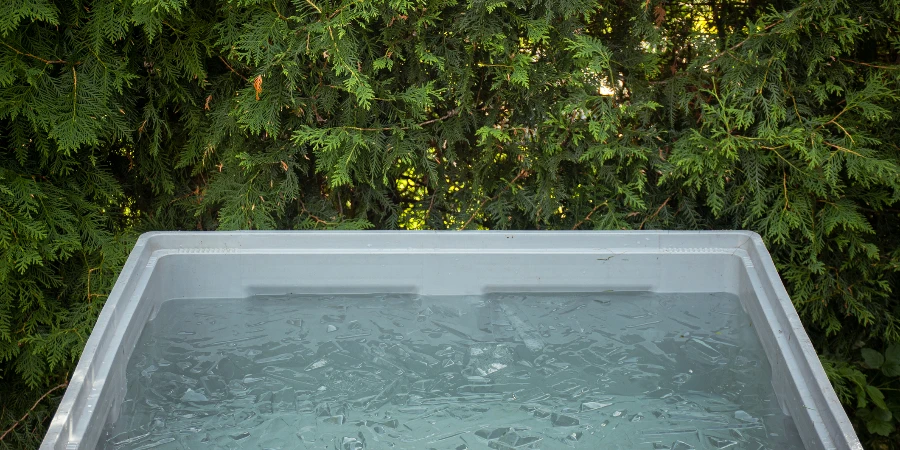 Portable plastic bath tub or tank in a garden ready for ice bathing in the cold water filled with ice cubes