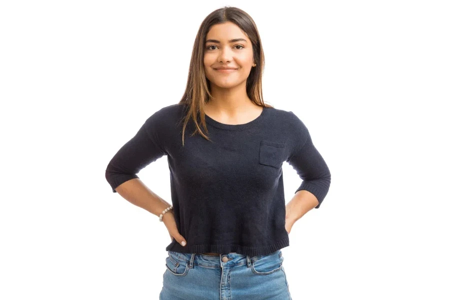 Portrait of female brunette in blue top standing against white background