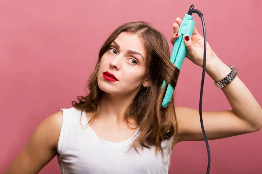 Pretty woman styling her hair with a curling iron