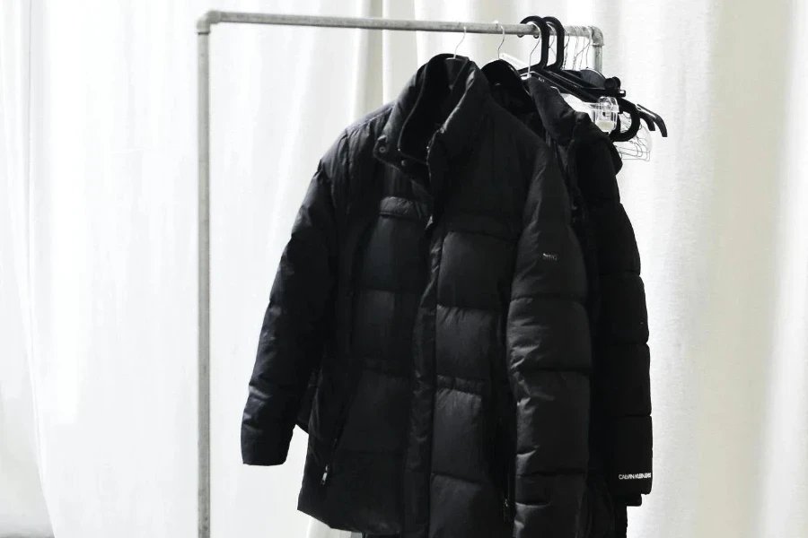 Rack with outerwear against curtains in light room