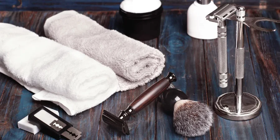 Razors, brush, blade, stand, perfume and towels on a dark wood background