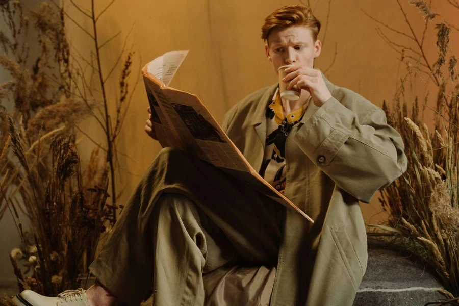 Redhead Model in Coat Reading Newspaper and Drinking Coffee