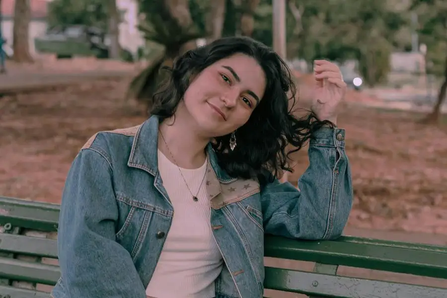 Serene Young Woman Sits on Bench in Park by Laura Oliveira