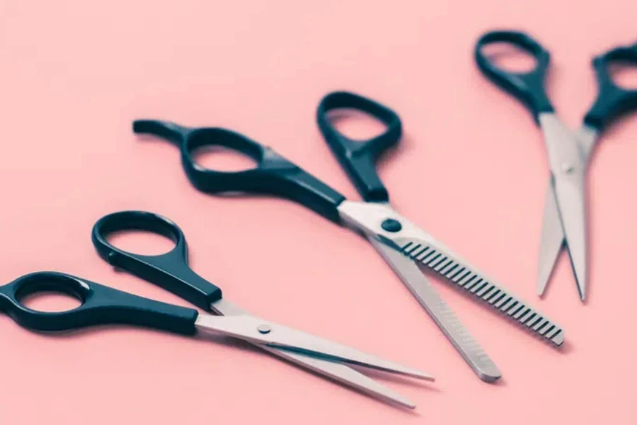 Set of three pairs of hairdresser's scissors on a pink background