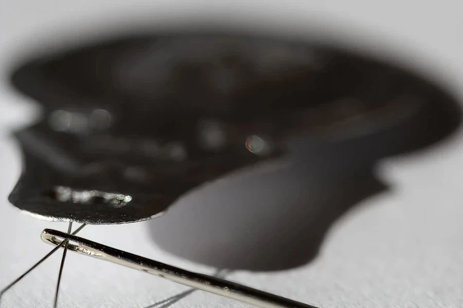 Sewing needle threader tool in use and a single black string