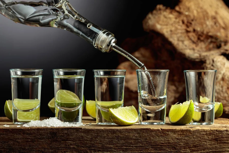 Silver Tequila with salt and lime slices on an old wooden board