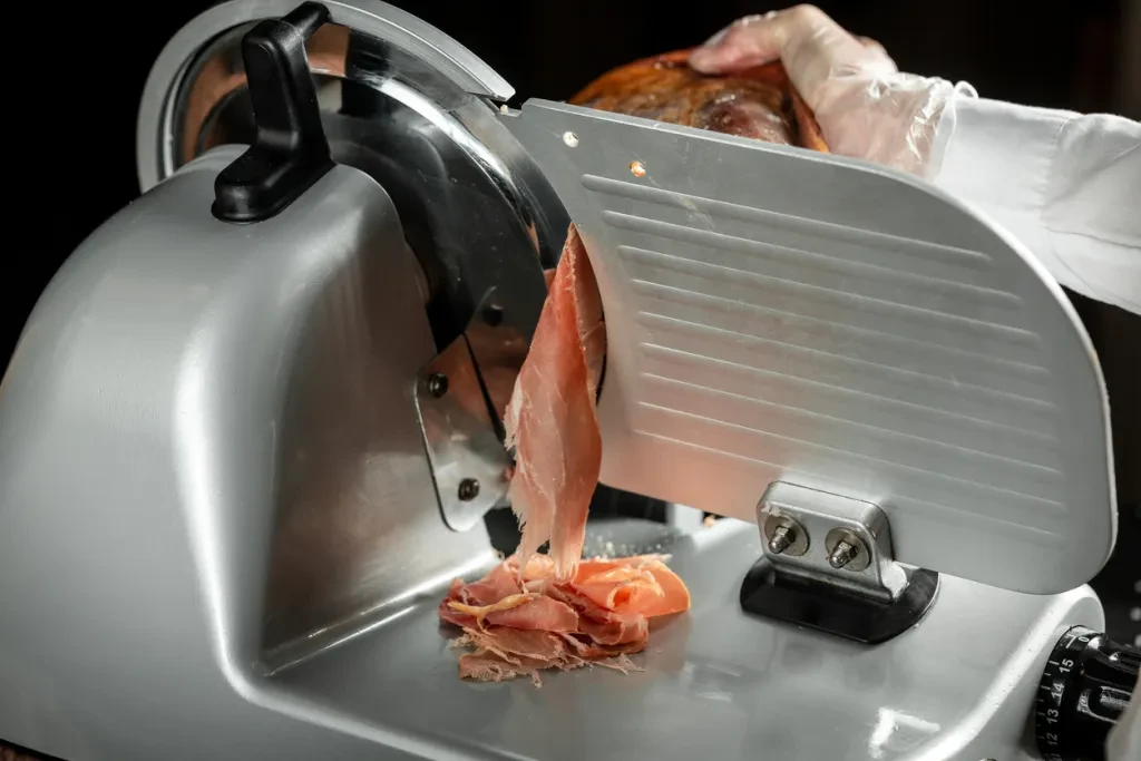 Slicing Spanish jamon iberico on cutting machine